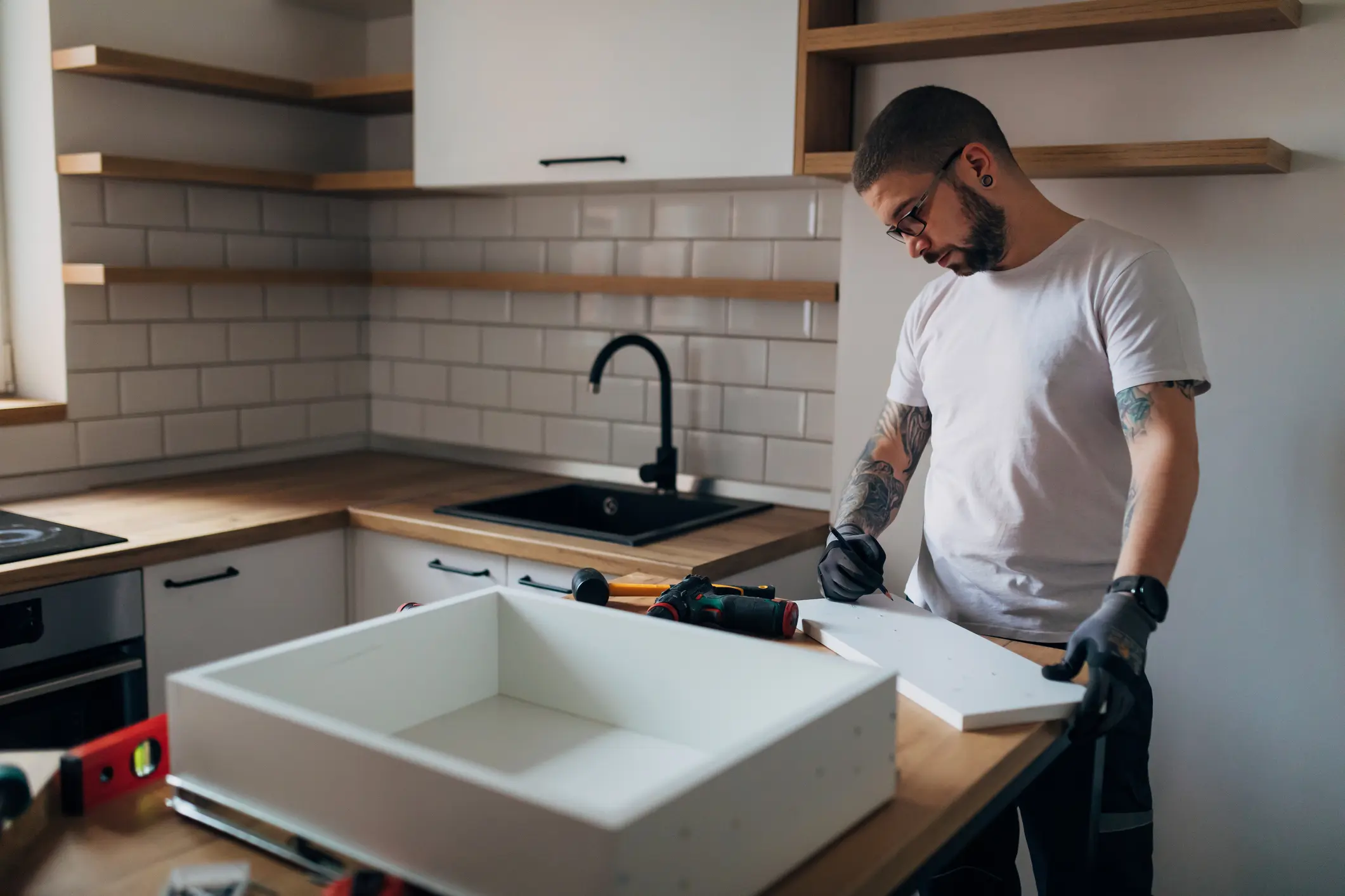 Man assembling furniture in modern kitchen.