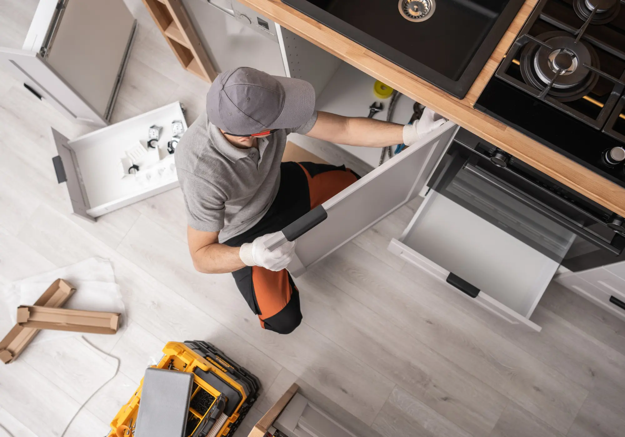 worker in uniform fixing, installing furniture and equipment in the kitchen, using screwdriver indoors. Furniture repair and assembly concept. Horizontal shot